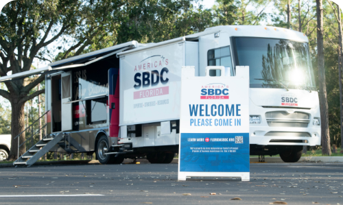 Image of FSBDC Mobile Assistance Center RV and a sign that says welcome.